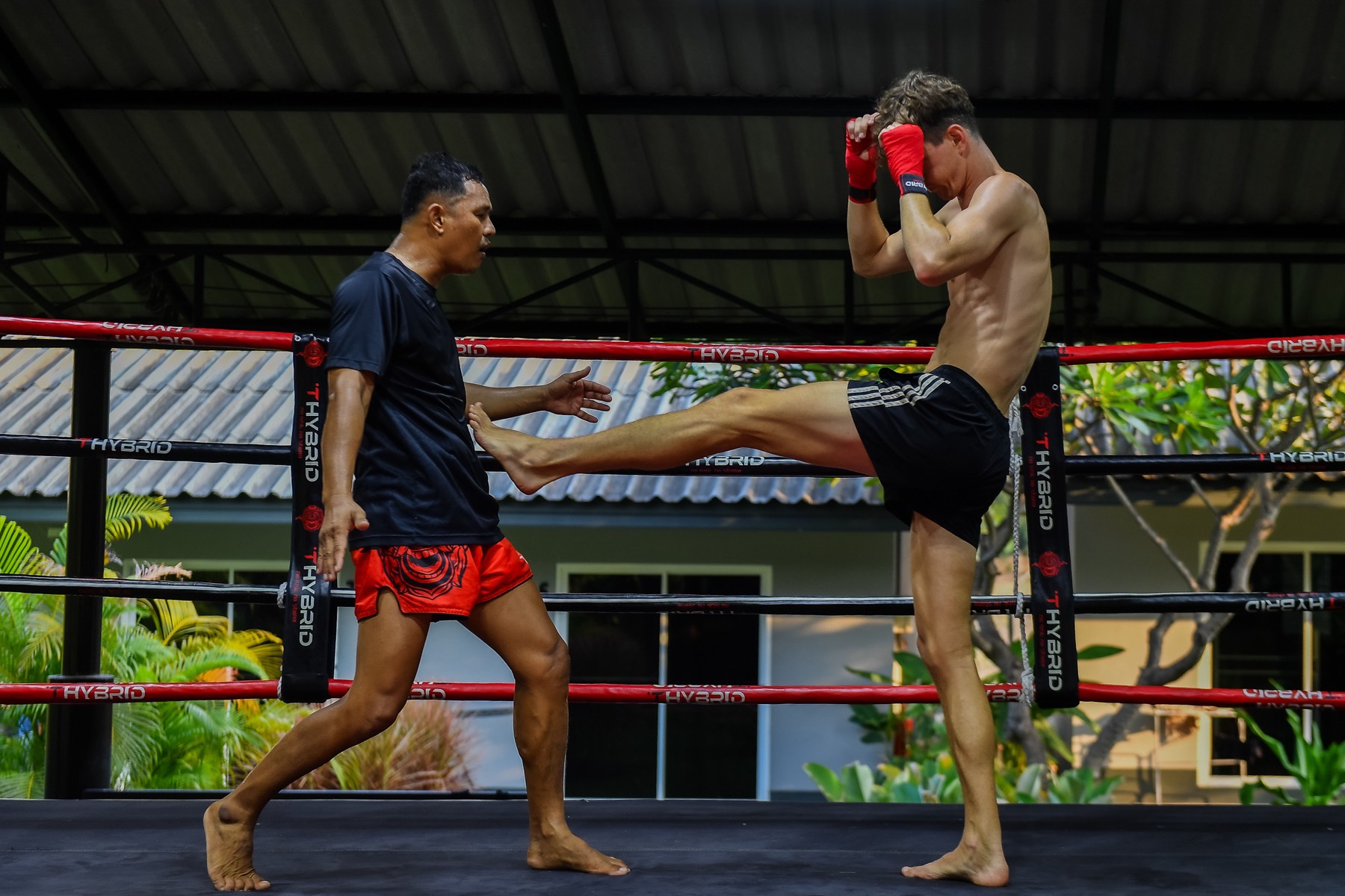 Muay Thai ring and heavy bag row under an open-sided shelter